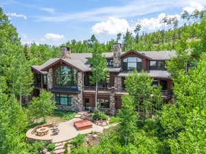 Back of property with a balcony, a patio, and an outdoor fire pit