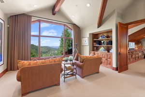 Living room with a mountain view, lofted ceiling with beams, and light colored carpet