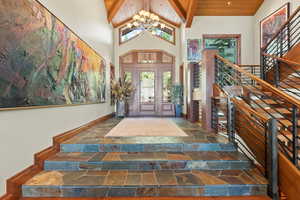 Foyer entrance with beamed ceiling, wooden ceiling, high vaulted ceiling, and an inviting chandelier