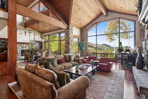 Sunroom featuring a mountain view, vaulted ceiling with beams, a fireplace, and wooden ceiling