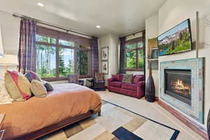 Bedroom with light colored carpet and a tiled fireplace