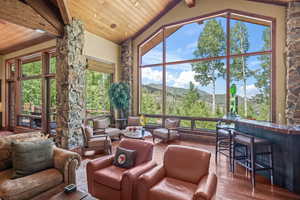 Sunroom / solarium featuring a mountain view, lofted ceiling with beams, wooden ceiling, and a healthy amount of sunlight