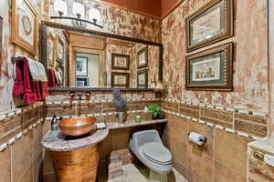 Bathroom with toilet, sink, and tile walls