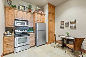 Kitchen with appliances with stainless steel finishes, tasteful backsplash, light tile patterned floors, and light brown cabinetry