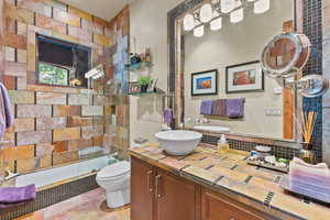 Bathroom with a shower with door, vanity, tile walls, and toilet