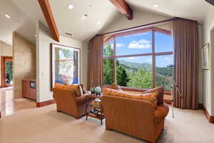 Living room with vaulted ceiling with beams, a mountain view, and light colored carpet