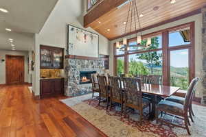 Dining area featuring dark hardwood / wood-style flooring, high vaulted ceiling, a mountain view, a fireplace, and wood ceiling