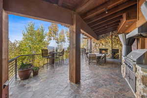 View of patio / terrace with an outdoor stone fireplace, a bar, area for grilling, and a grill