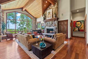 Living room featuring hardwood / wood-style floors, a fireplace, high vaulted ceiling, and beamed ceiling