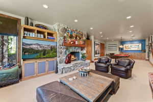 Living room with a stone fireplace, light colored carpet, and pool table