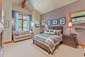 Carpeted bedroom featuring vaulted ceiling with beams