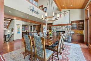 Dining room featuring wooden ceiling, high vaulted ceiling, a chandelier, wood-type flooring, and a fireplace