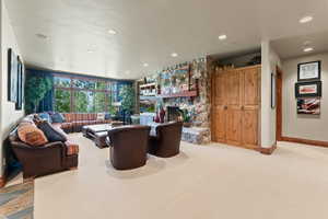 Living room featuring a stone fireplace and light carpet