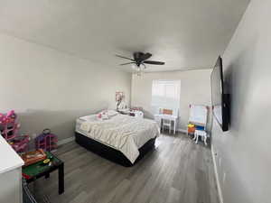Bedroom featuring ceiling fan, hardwood / wood-style floors, and a textured ceiling