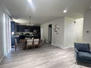 Dining area with sink, light hardwood / wood-style floors, and an inviting chandelier
