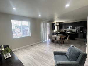 Living room with light wood-type flooring, sink, and an inviting chandelier