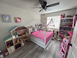Bedroom with a textured ceiling, hardwood / wood-style flooring, and ceiling fan