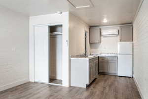 Kitchen with hardwood / wood-style floors, white refrigerator, a wall mounted AC, and brick wall