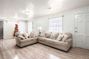 Living room featuring wood walls, wood-type flooring, and a textured ceiling