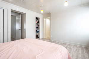 Bedroom featuring light wood-type flooring, ornamental molding, and a closet