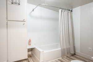 Bathroom with hardwood / wood-style floors, a textured ceiling, and shower / tub combo with curtain