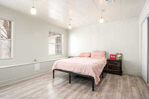 Bedroom featuring light hardwood / wood-style flooring, multiple windows, and ornamental molding