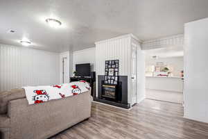 Living room featuring a tile fireplace, wood-type flooring, and a textured ceiling