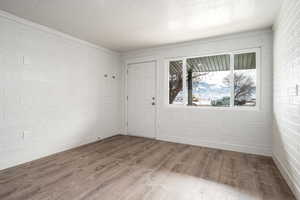 Empty room with hardwood / wood-style flooring, a textured ceiling, and brick wall