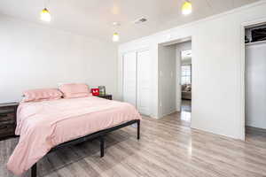 Bedroom featuring light wood-type flooring, a closet, and ornamental molding