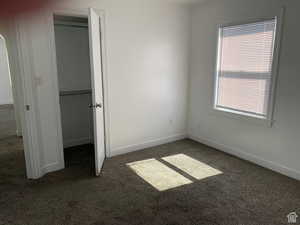 Unfurnished bedroom with dark carpet and multiple windows