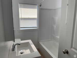 Full bathroom featuring a healthy amount of sunlight, toilet, sink, and bathtub / shower combination