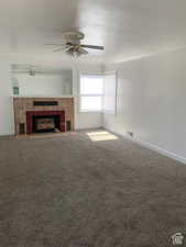 Unfurnished living room featuring ceiling fan, carpet floors, and a tiled fireplace