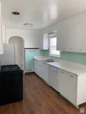 Kitchen with white cabinets, dark hardwood / wood-style floors, white appliances, and sink