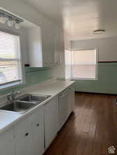 Kitchen with white cabinetry, sink, white dishwasher, and dark hardwood / wood-style floors