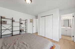 Bedroom featuring ensuite bathroom, a closet, sink, and light hardwood / wood-style flooring