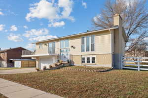 View of front facade featuring a garage, a balcony, and a front yard