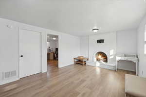 Unfurnished living room featuring a fireplace and light hardwood / wood-style flooring