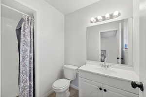 Bathroom with tile patterned flooring, vanity, toilet, and curtained shower