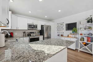 Kitchen featuring white cabinetry, light stone counters, and stainless steel appliances