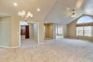 Interior space featuring ceiling fan with notable chandelier and lofted ceiling