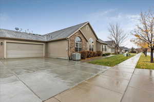 View of side of home featuring a garage, a lawn, and central air condition unit