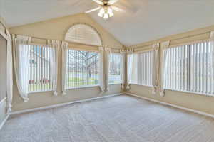 Unfurnished sunroom with vaulted ceiling, ceiling fan, and a healthy amount of sunlight