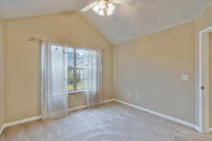 Empty room with light carpet, ceiling fan, and lofted ceiling