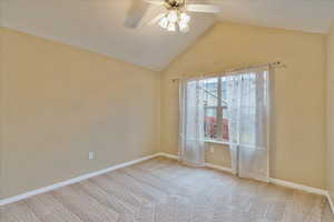 Empty room with carpet flooring, vaulted ceiling, and ceiling fan