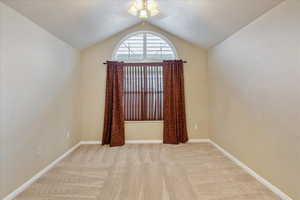 Carpeted empty room with a textured ceiling, vaulted ceiling, and ceiling fan