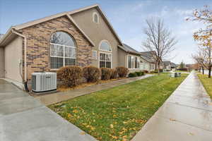 View of side of home featuring central AC unit and a yard