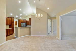 Kitchen featuring stainless steel fridge, light colored carpet, hanging light fixtures, and an inviting chandelier