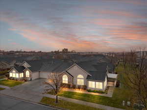 View of front of property featuring central air condition unit, a lawn, and a garage