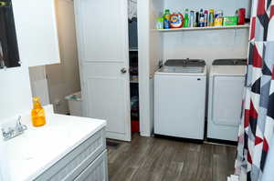 Washroom with sink, dark hardwood / wood-style flooring, and independent washer and dryer