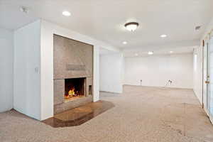 Unfurnished living room with carpet flooring and a large fireplace